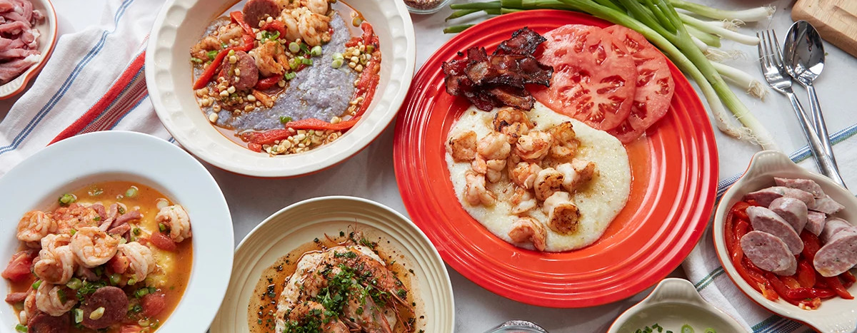top down of several dishes of shrimp and grits, sausage, tomatoes