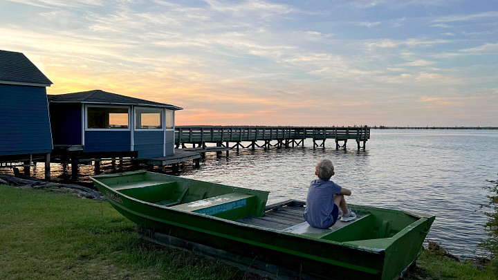 child sitting on a boat next to the lake, pier 