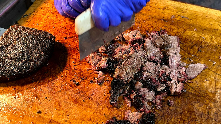 barbecue being chopped on wooden cutting board