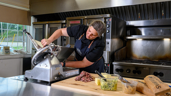 chef slicing meat in professional kitchen