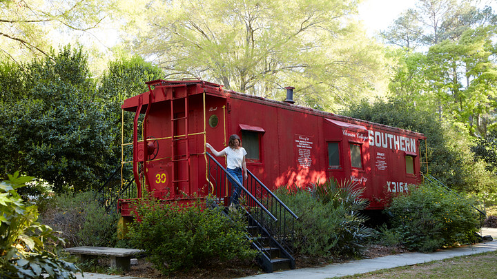 woman exiting red train car, botanical garden