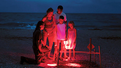 family on the beach at night with red light lanterns
