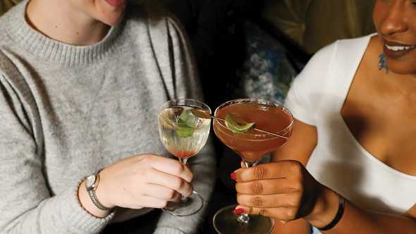 two women clinking cocktail glasses