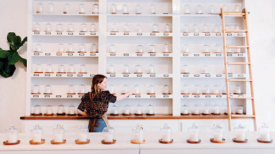 woman in candle store, rows on candles, rolling ladder